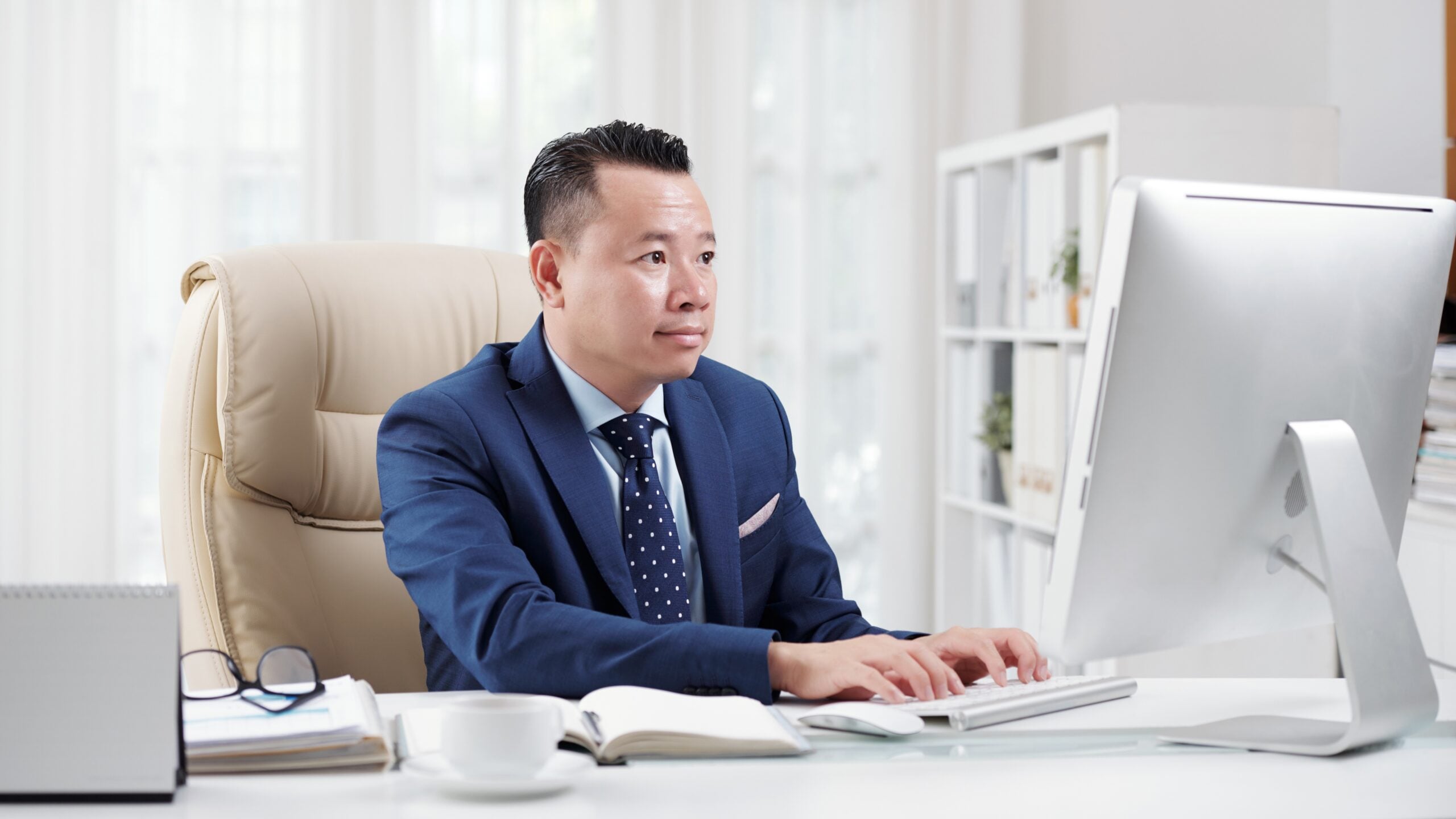 malaysian outsourced offshore sales manager in an office typing on a desktop