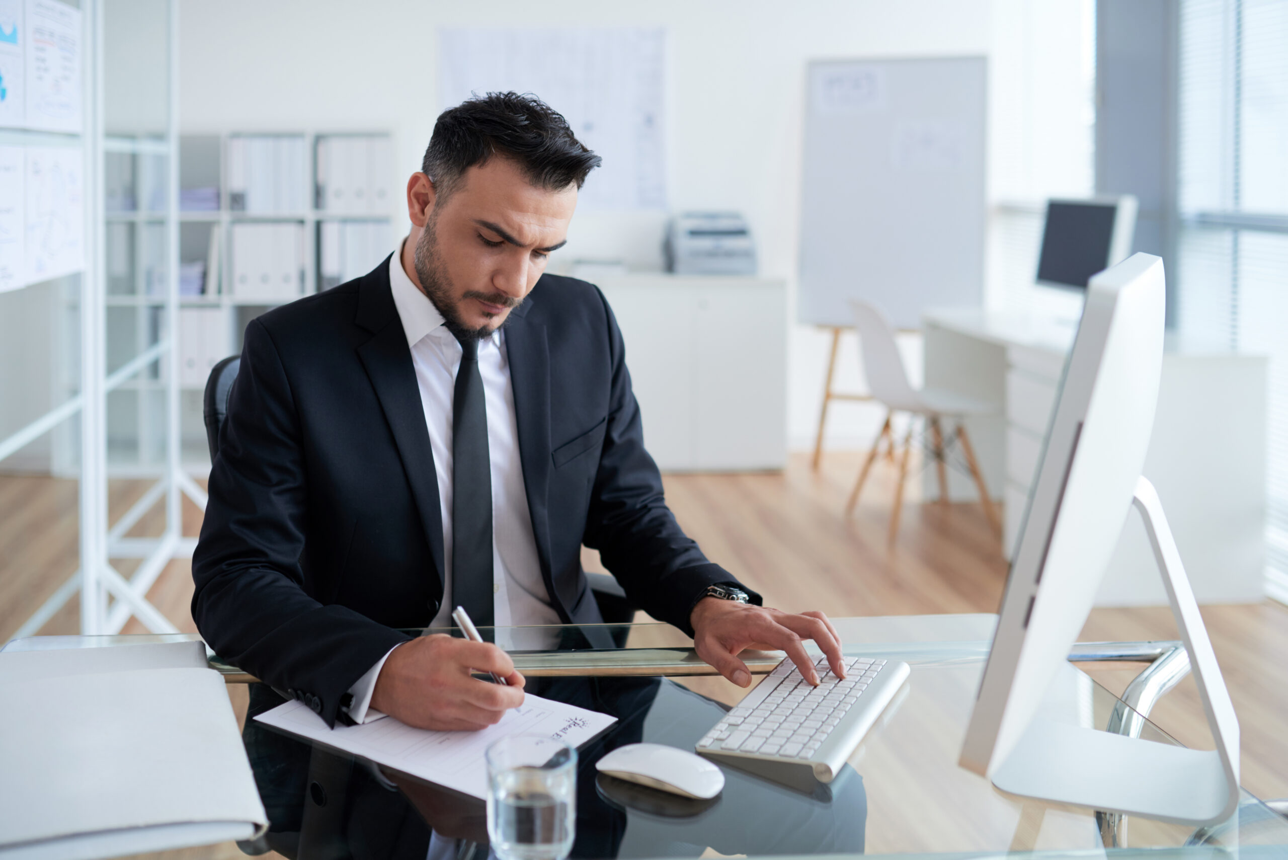 outsourced compliance officer in argentina writing notes on a table with a monitor