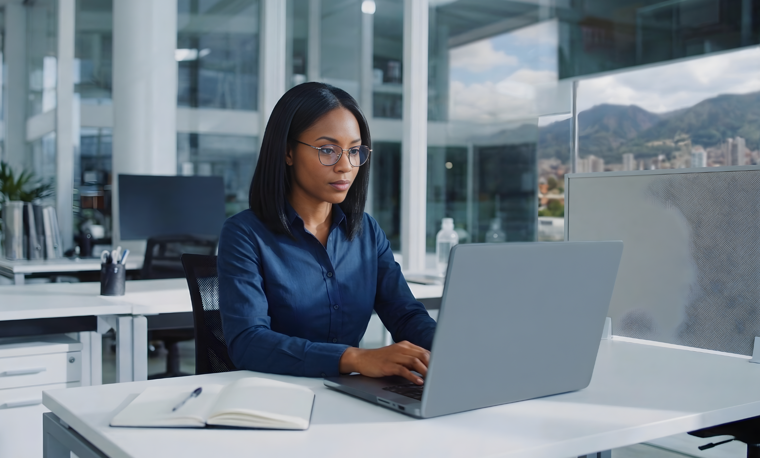 outsourced remote salesforce administrator typing on a laptop with a notebook and pen on the table