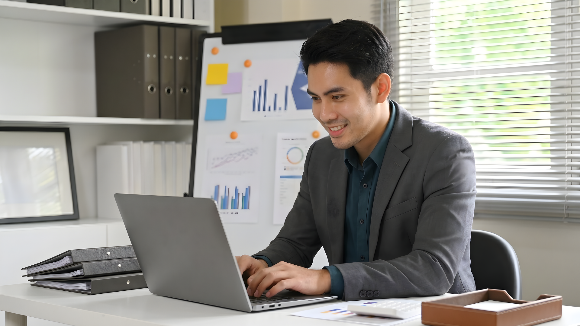 remote commercial analyst in malaysia working with a laptop while having a bulletin board with company data on the background