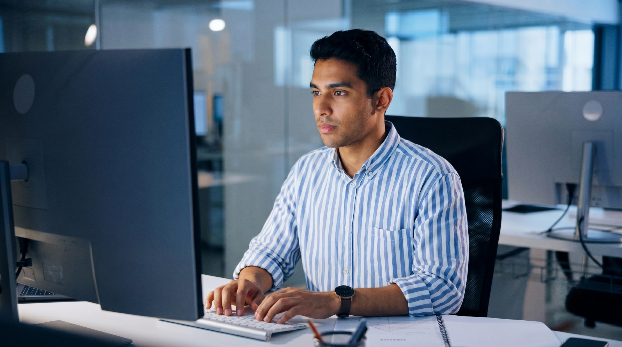 offshore cloud engineer in India working late at night on a computer in an open-plan office