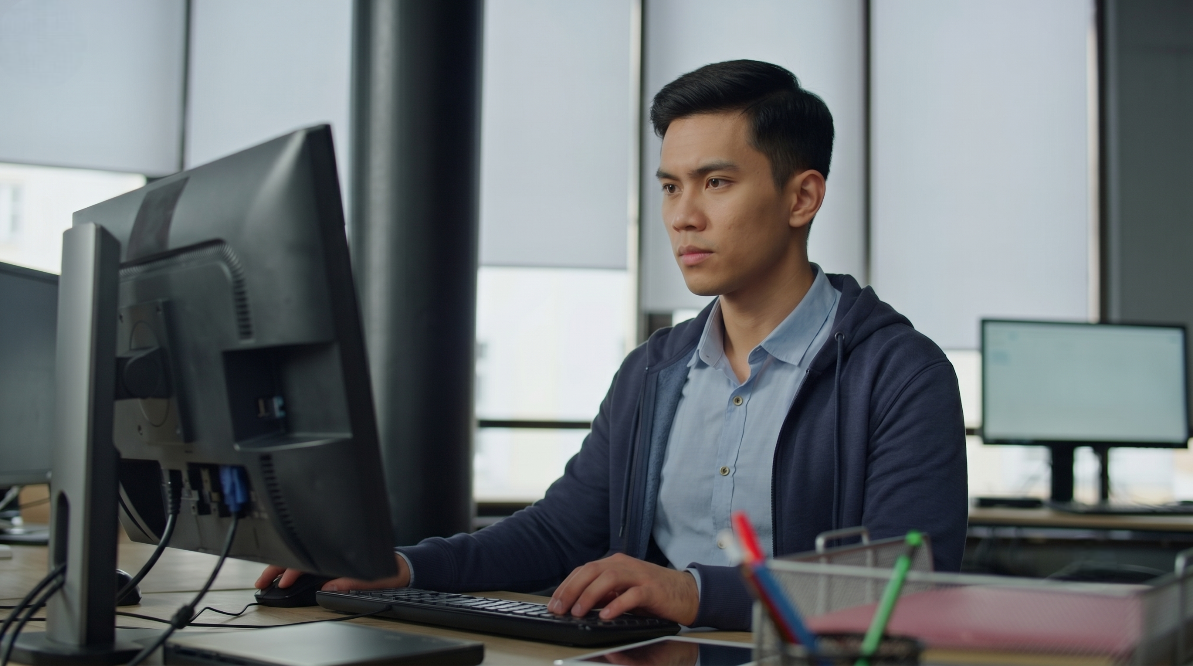 offshore cloud engineer in Malaysia working diligently on a computer in a modern office setup