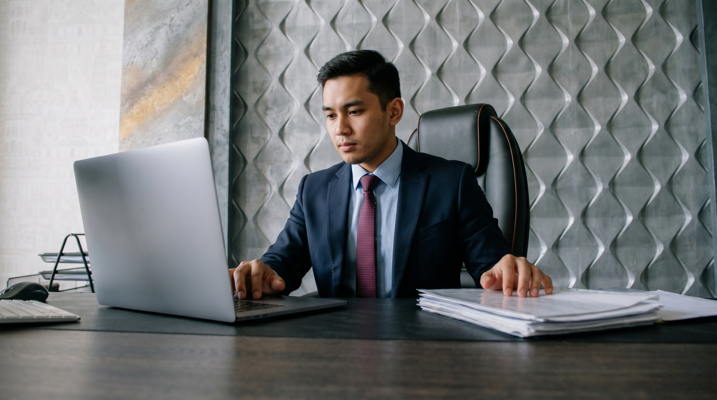Professional executive utilizing cost accountant outsourcing services to manage financial paperwork on a laptop