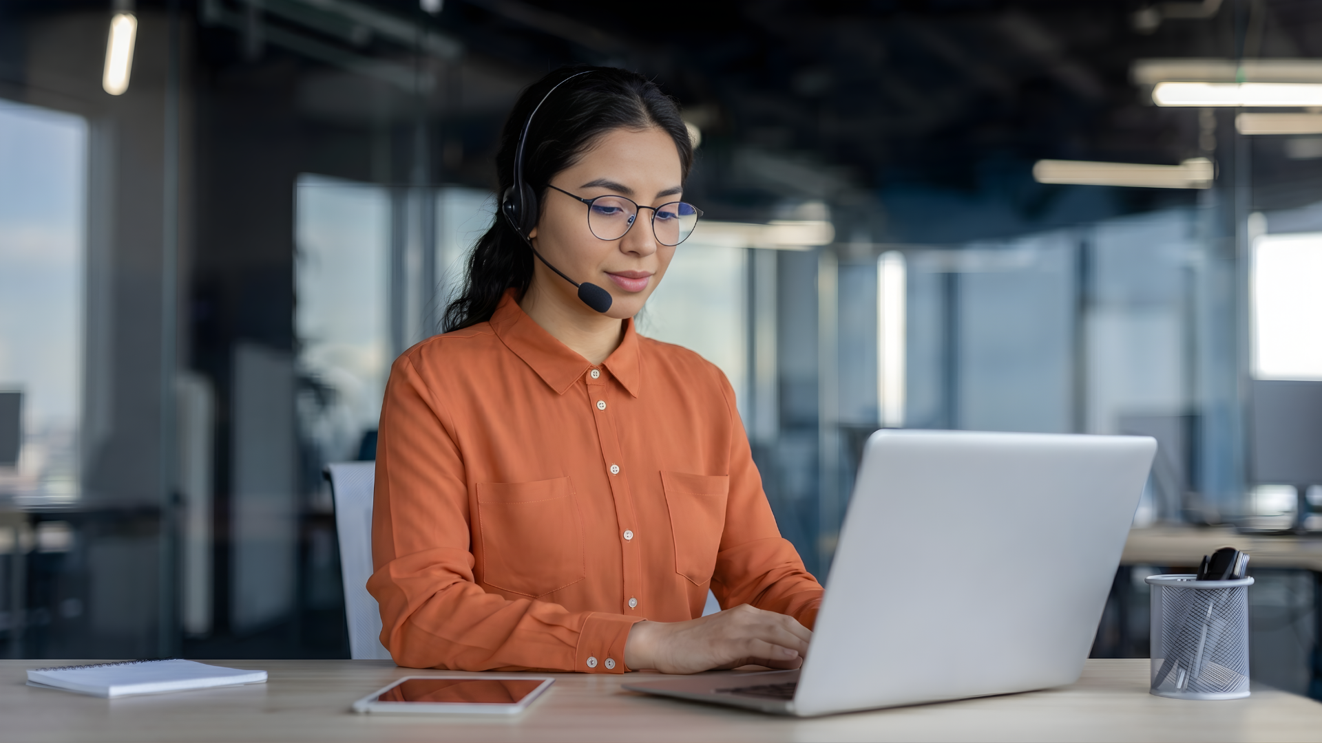 professional remote customer retention specialist wearing a headset and working on a laptop in a bright office space