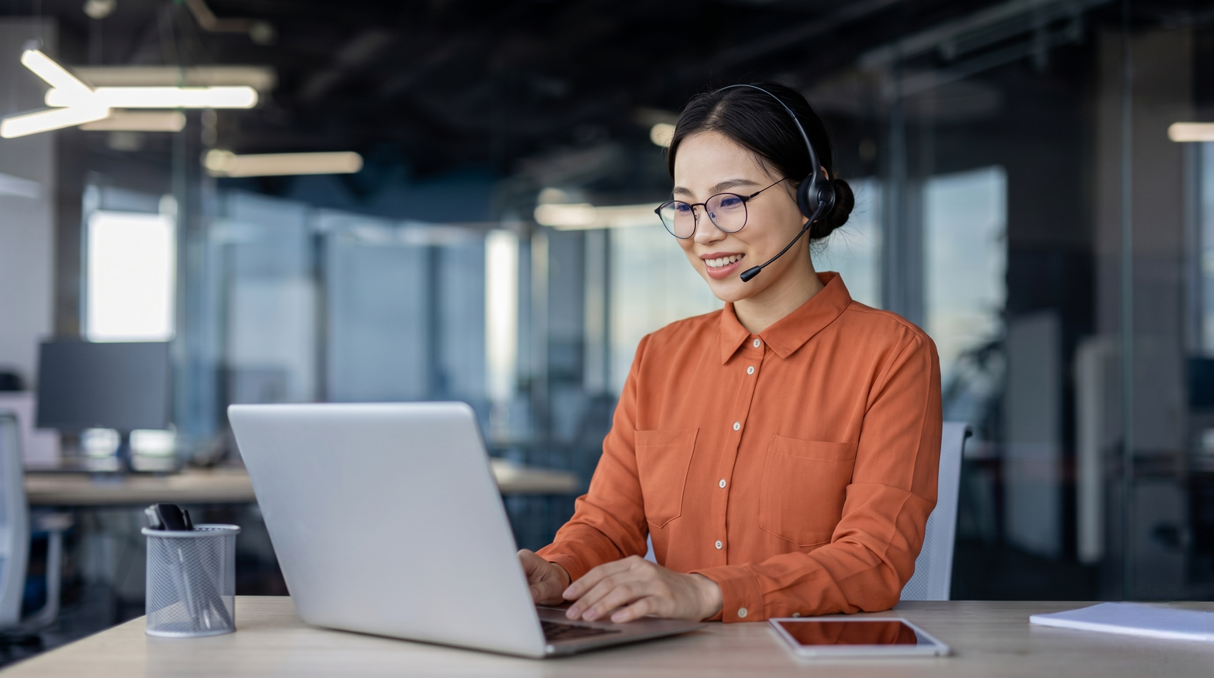 virtual help desk support specialist wearing glasses and a headset while providing customer assistance via her laptop