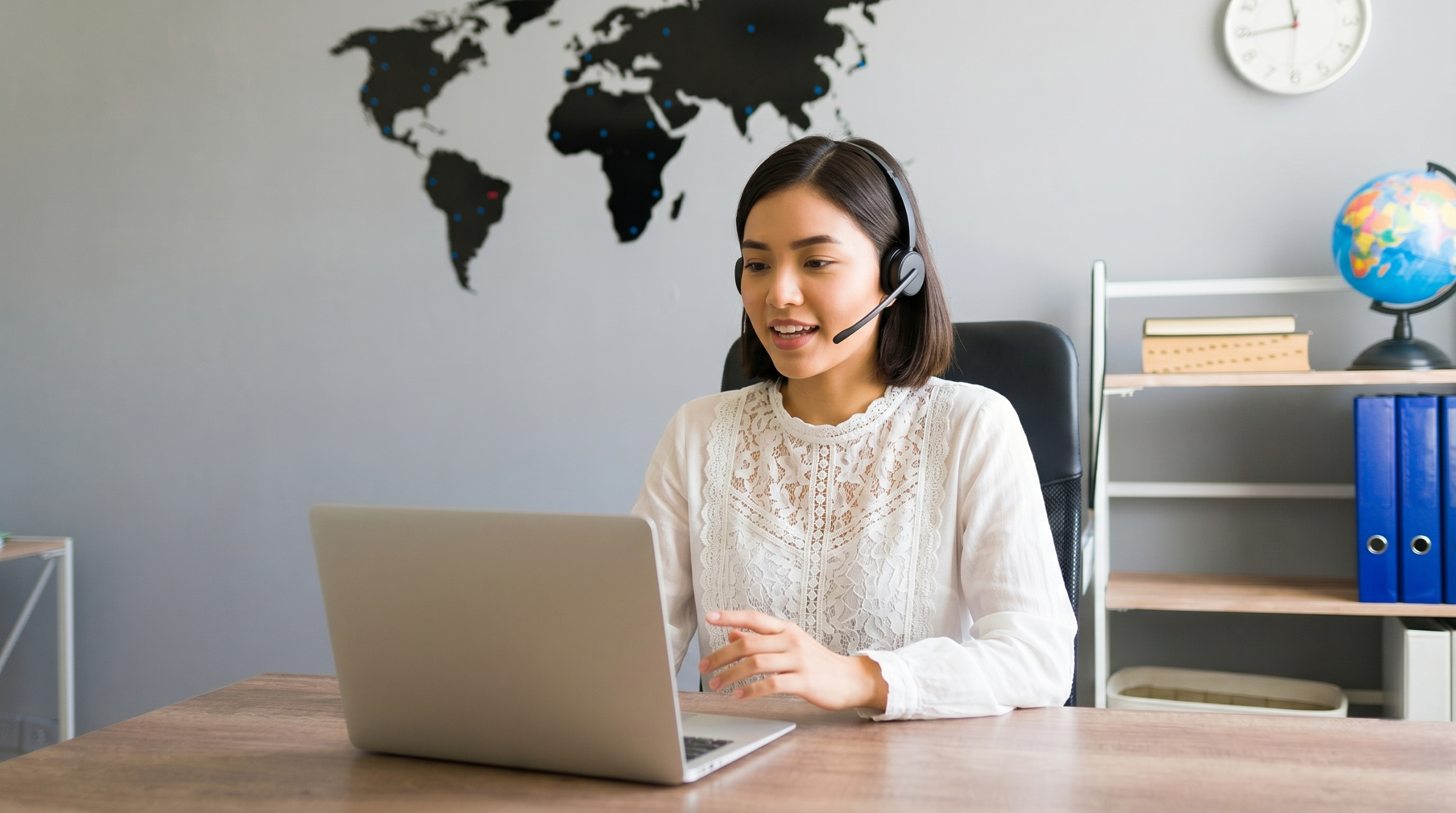 outsourced logistics coordinator in Vietnam working remotely on a laptop with a slim headset in a modern office setup