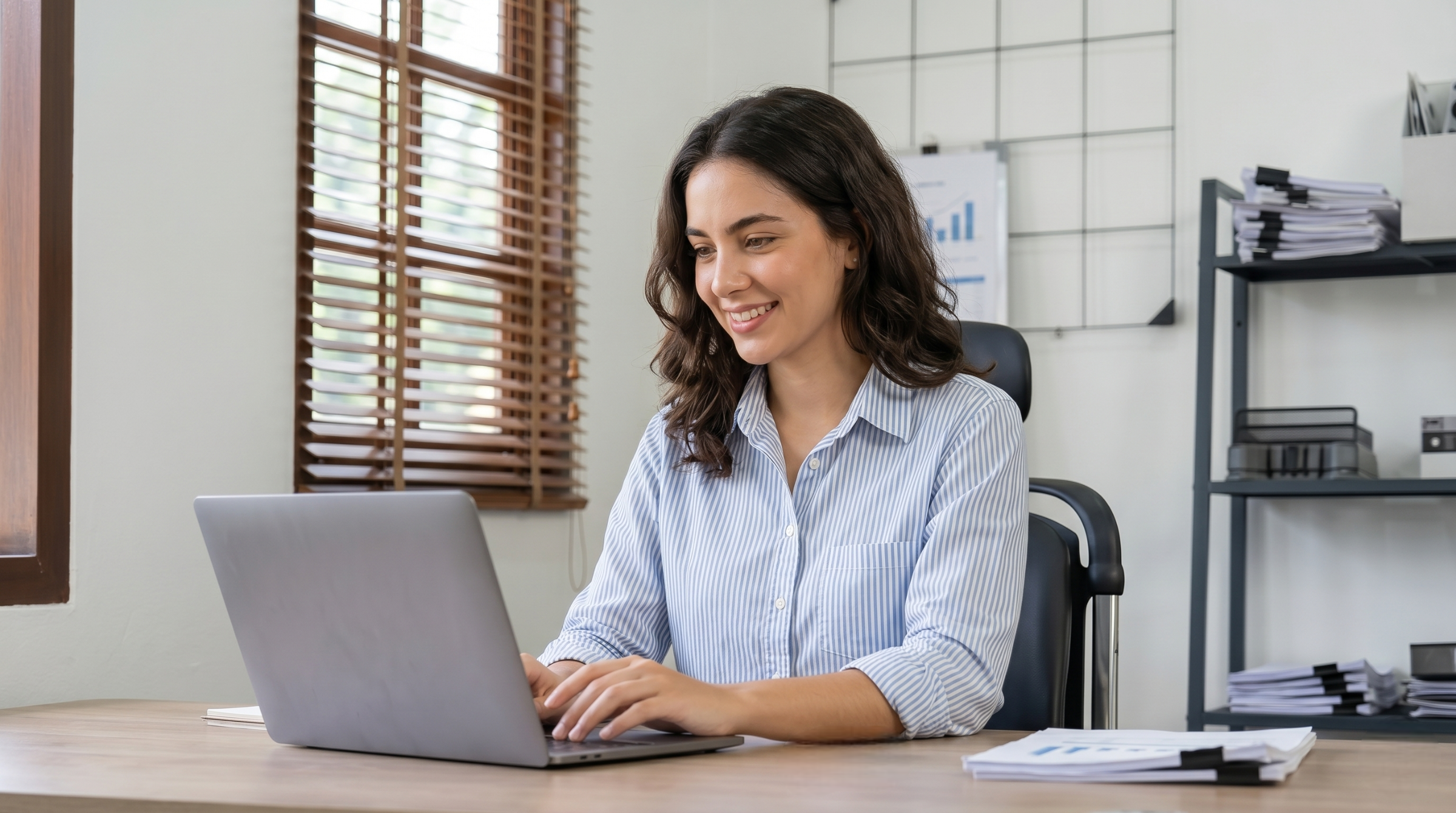 female remote supply chain planner in Argentina typing on her laptop at a bright, well-organized desk