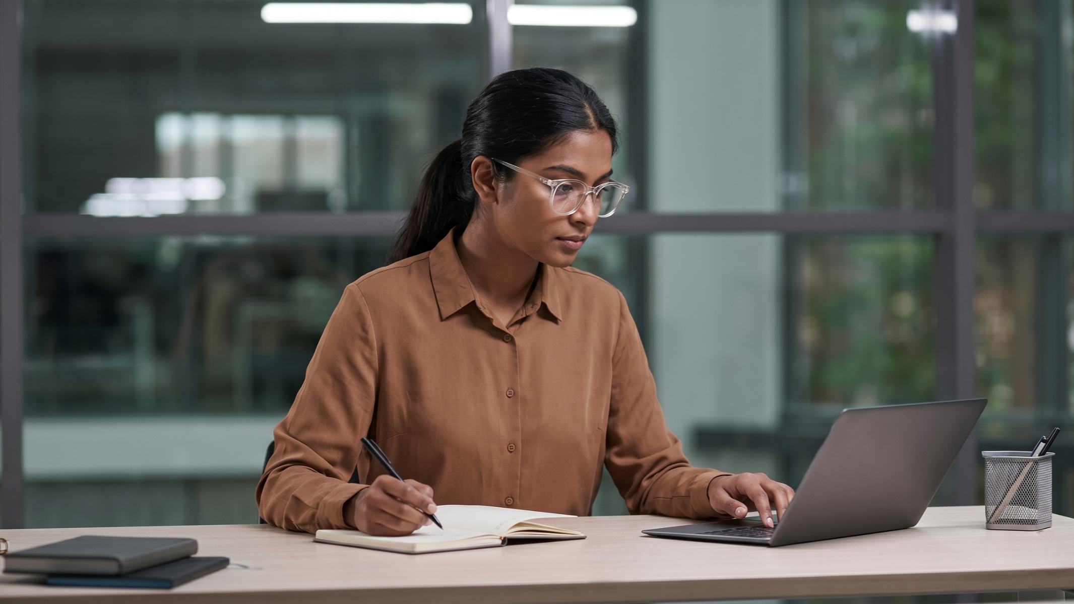 indan remote underwriter working with a laptop and writing on a notebook