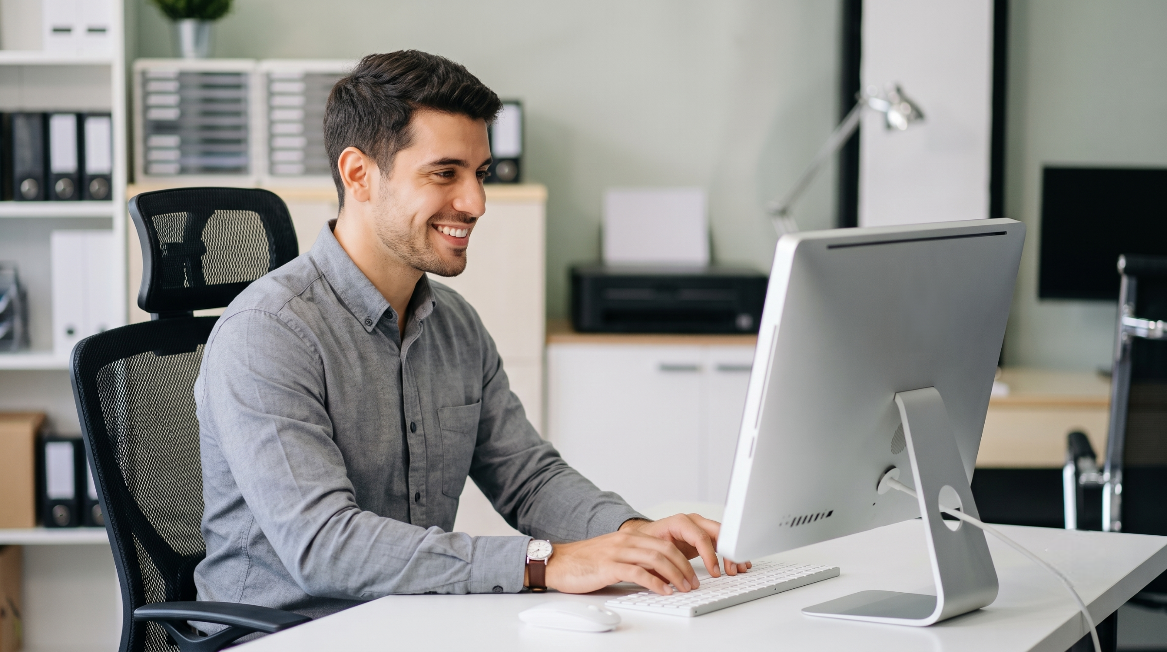 male offshore data entry officer typing on a desktop computer in a modern office environment