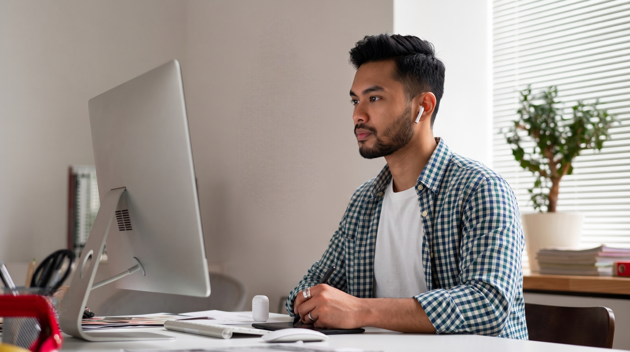 A professional remote image editor in Malaysia working at a desktop computer using a graphics tablet