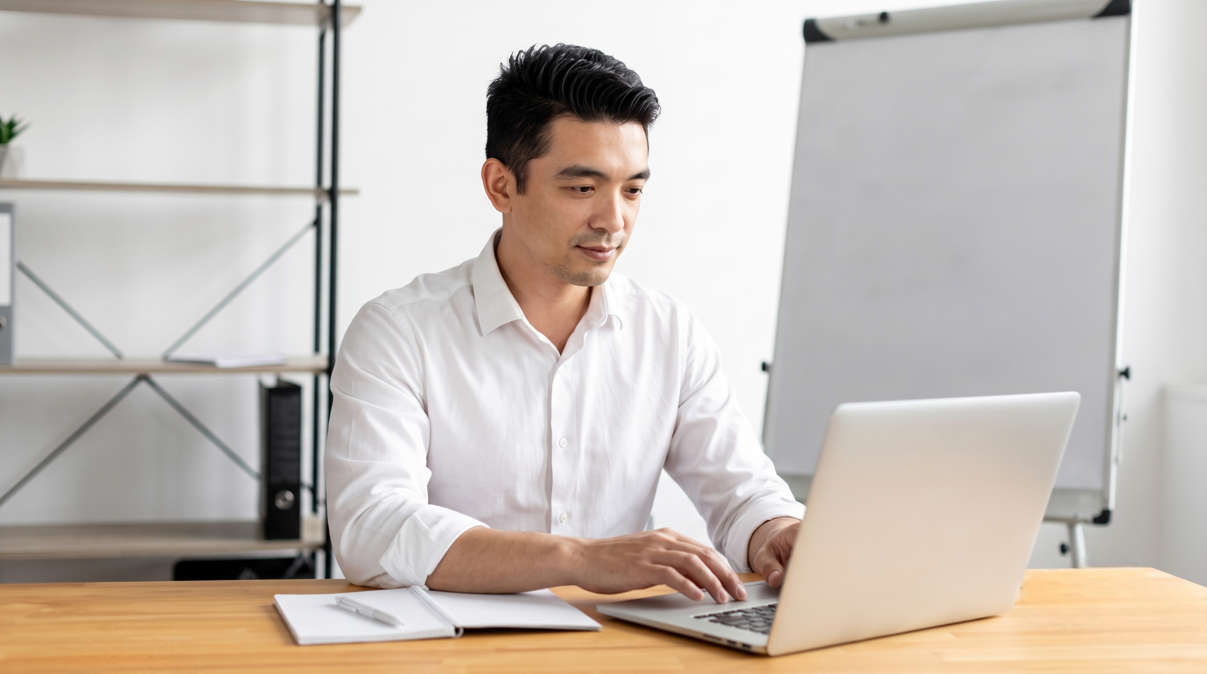 offshore property management professional in Malaysia wearing a white shirt and typing on a laptop