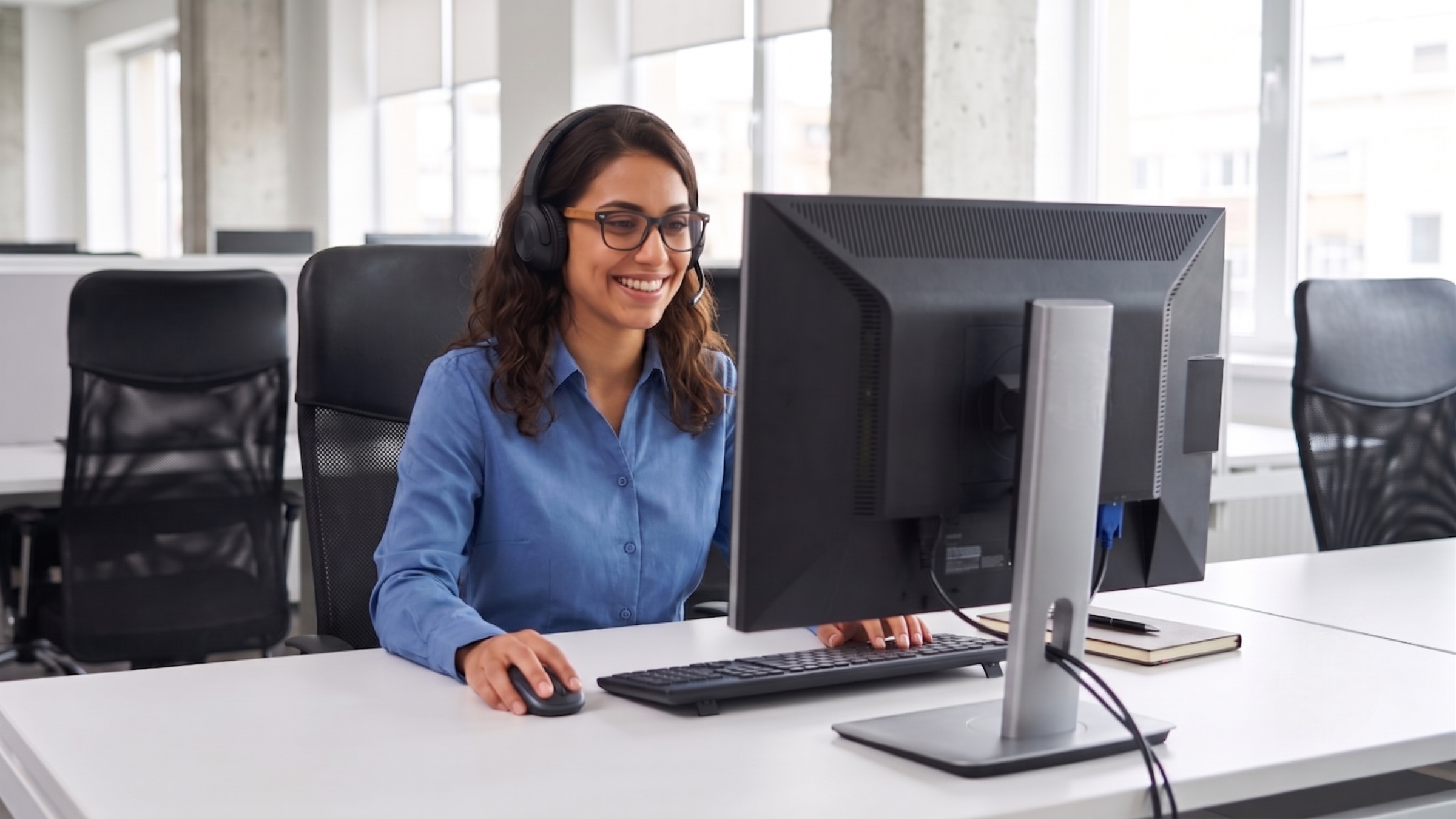 Argentine female service coordinator working remote at a desk with a monitor and headset