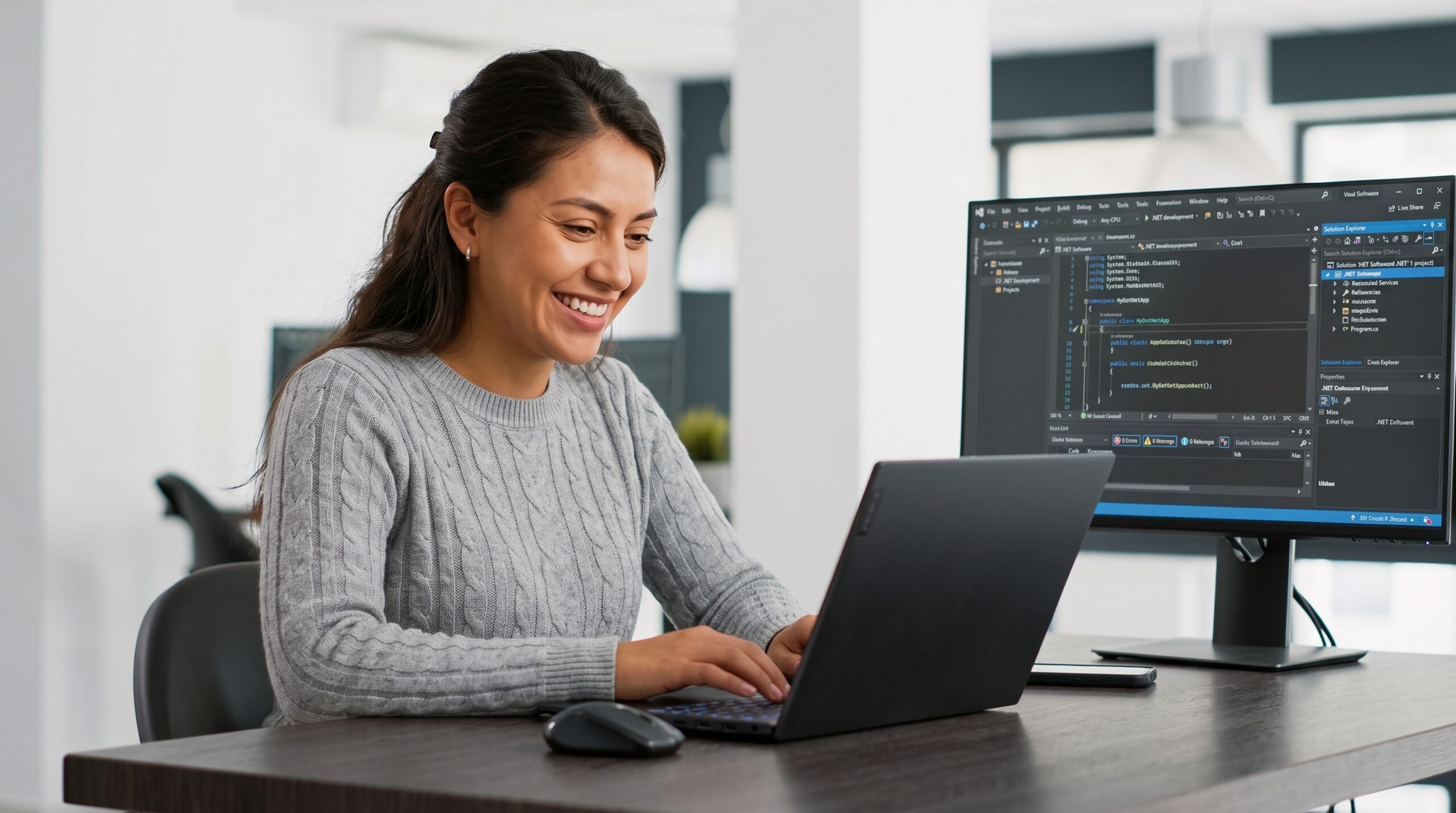 Latina developer working on laptop in modern office, illustrating .NET development outsourcing team