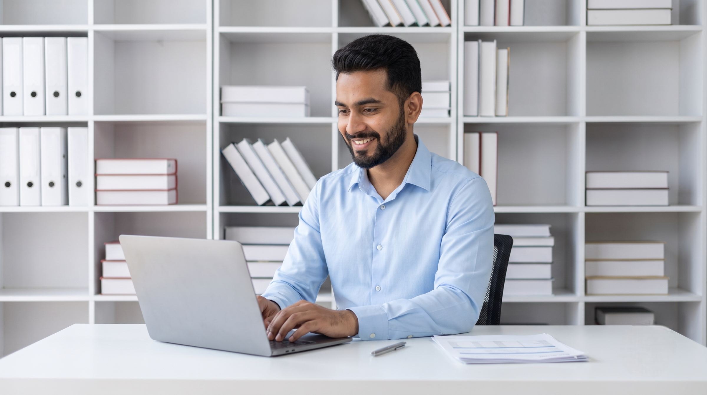 Professional assisting with bid management outsourcing using a laptop in a clean office
