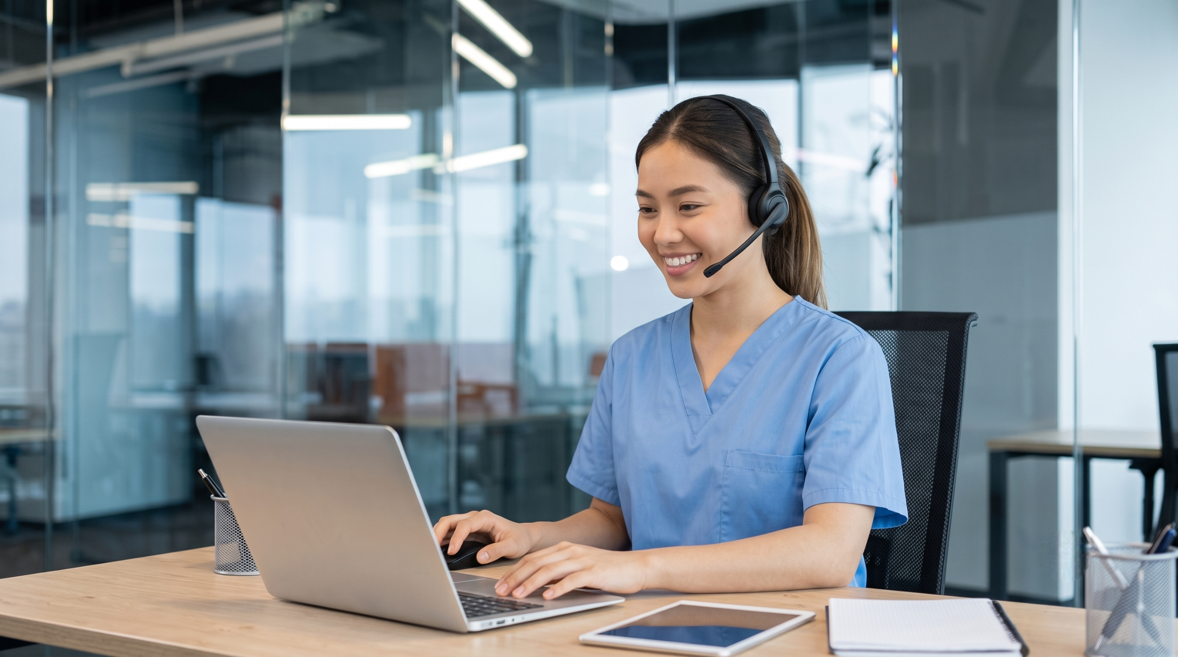 Vietnamese female telemedicine patient navigator typing on laptop at workstation