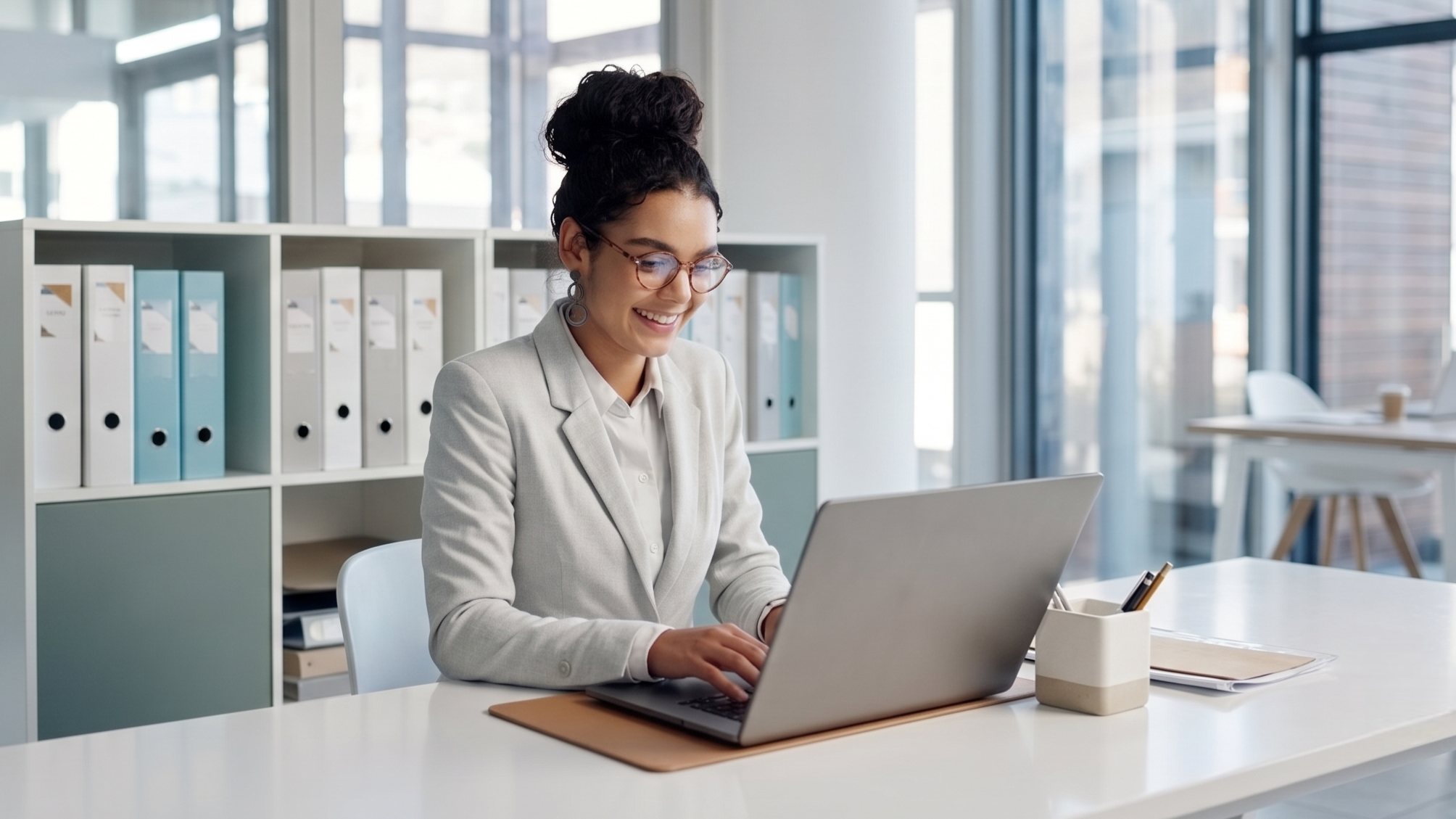 Smiling remote bid specialist typing on a laptop at a modern organized desk
