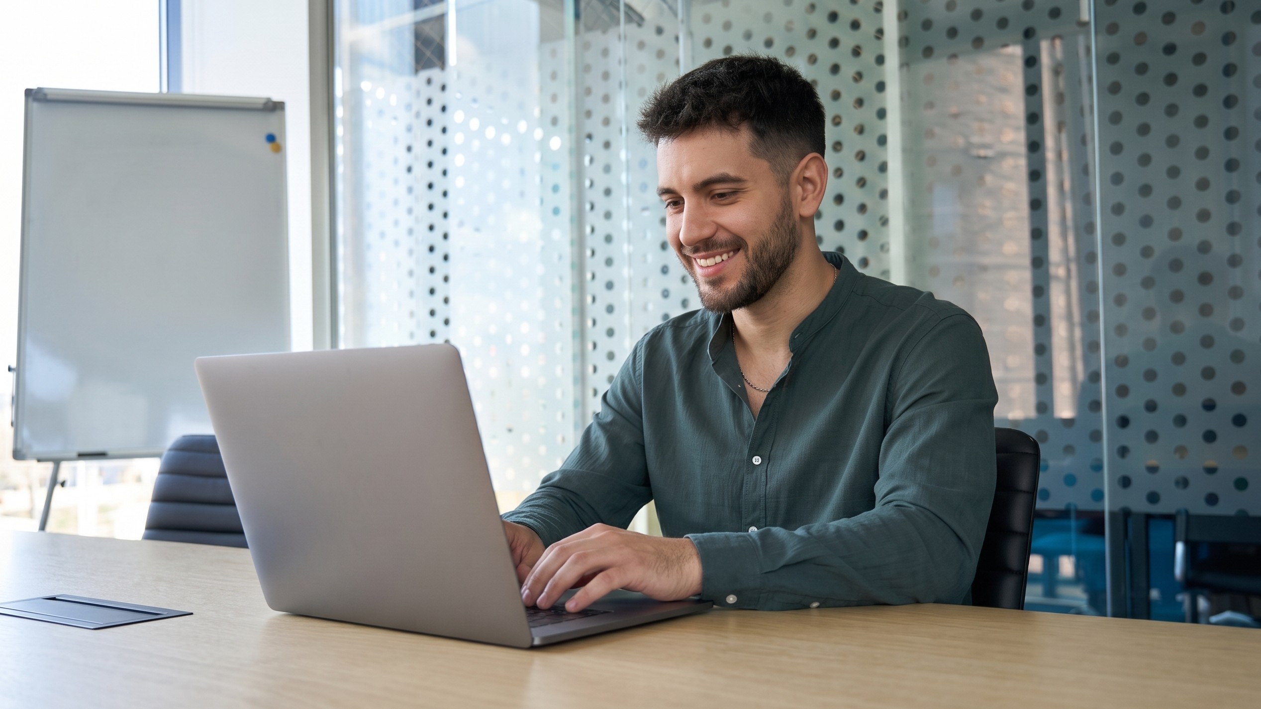 Outsourced database administrator working comfortably on a laptop in a modern conference room setup