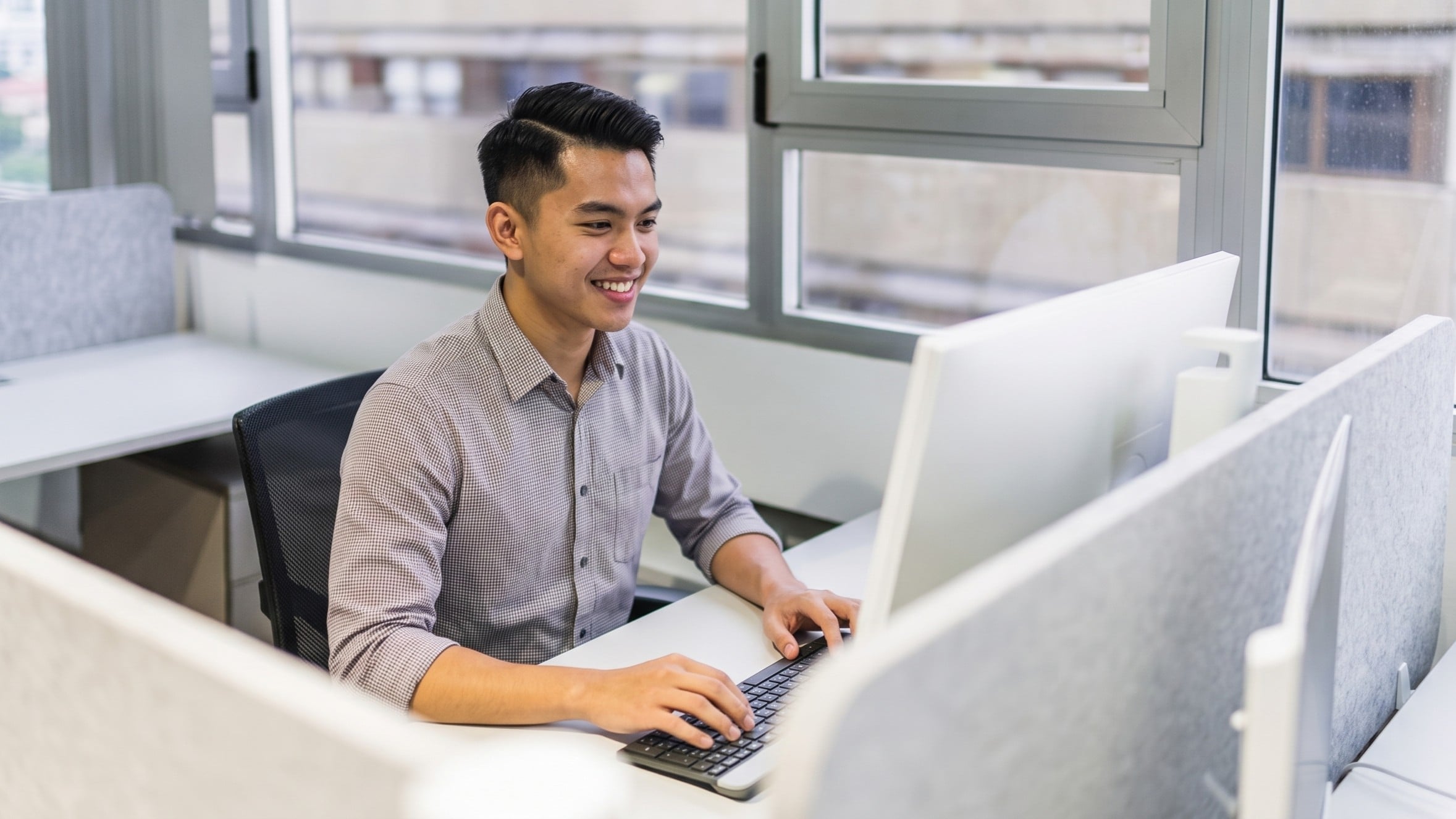 Qualified remote database administrator smiling while monitoring setup from a office workspace