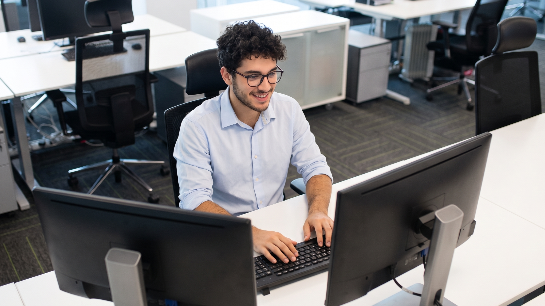 Professional working at dual desktop monitors for scrum master staffing solutions