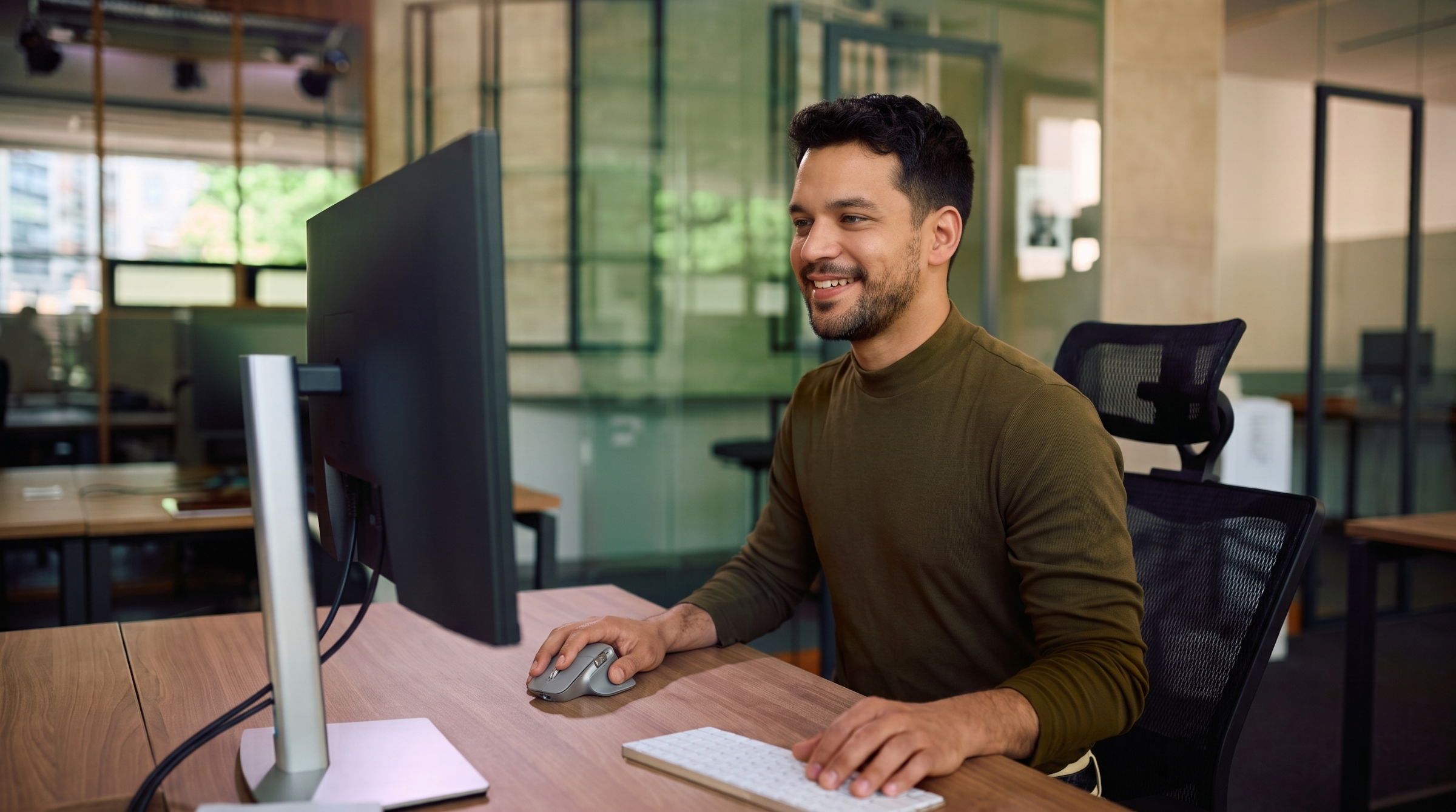 Male IT professional looking at a large desktop monitor, part of an outsourced soc team