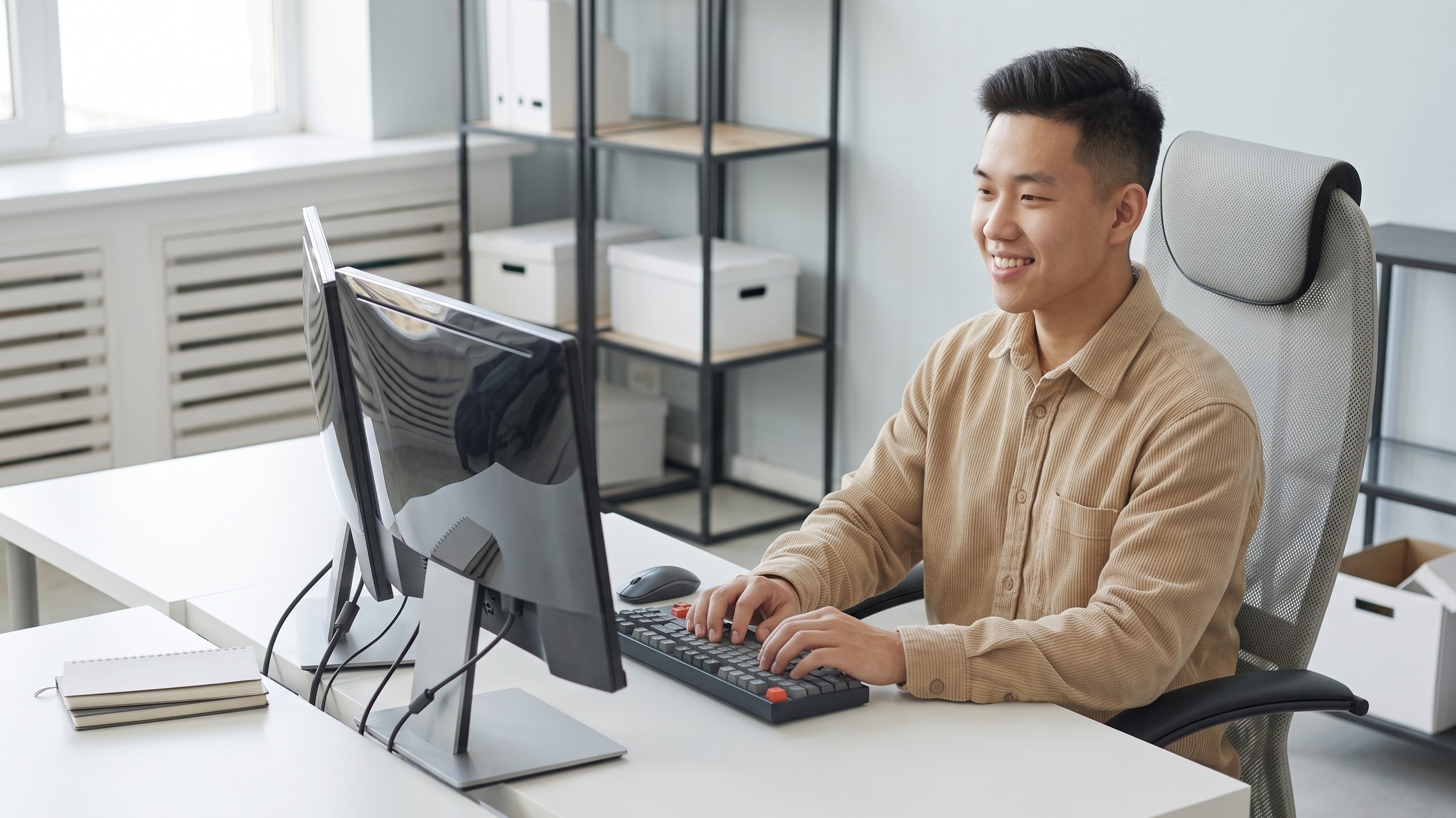 Offshore systems analyst reviewing computer code while working at a clean dual-monitor workstation