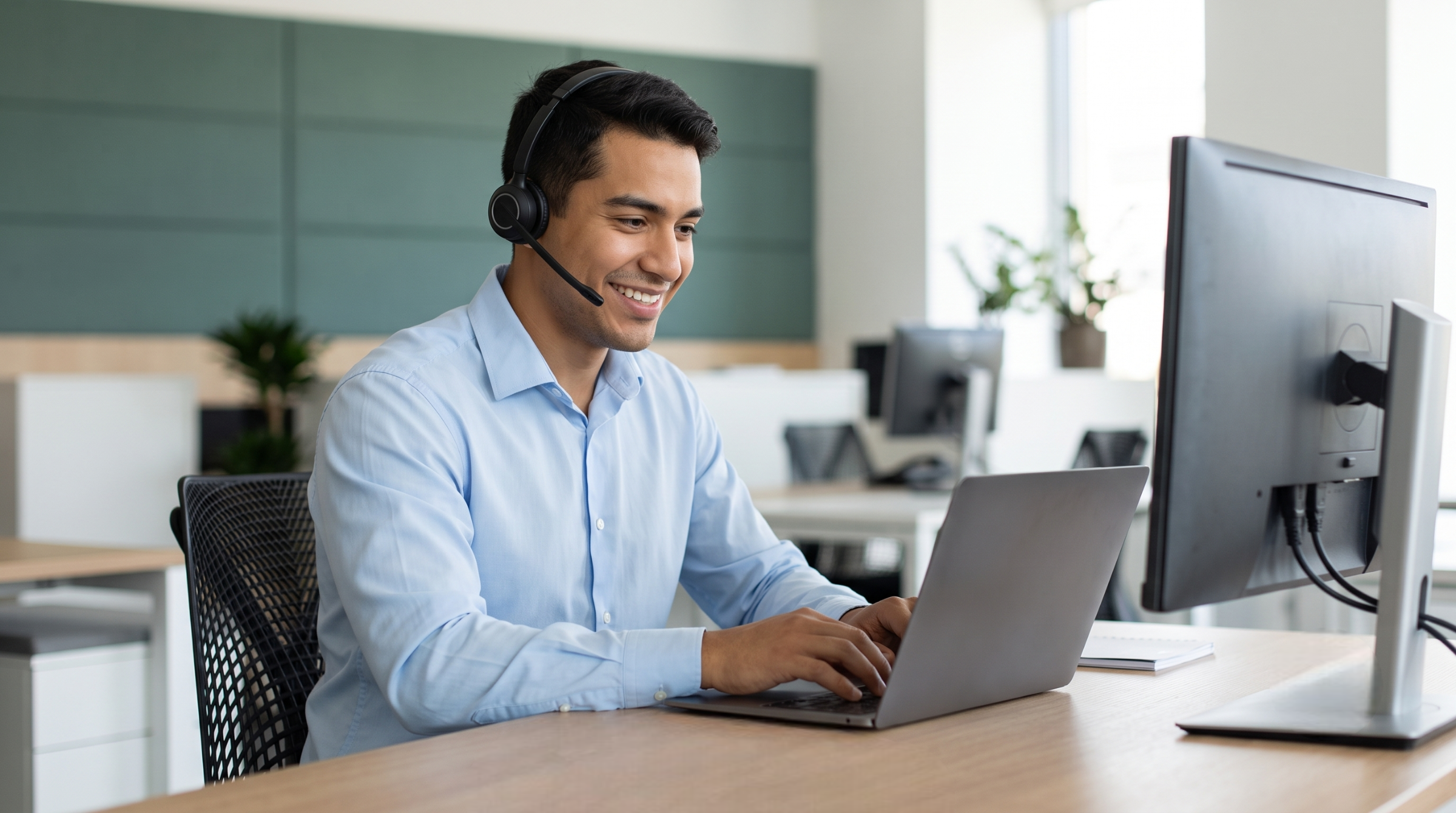 Male professional solutions specialist interacting with a desktop computer and laptop