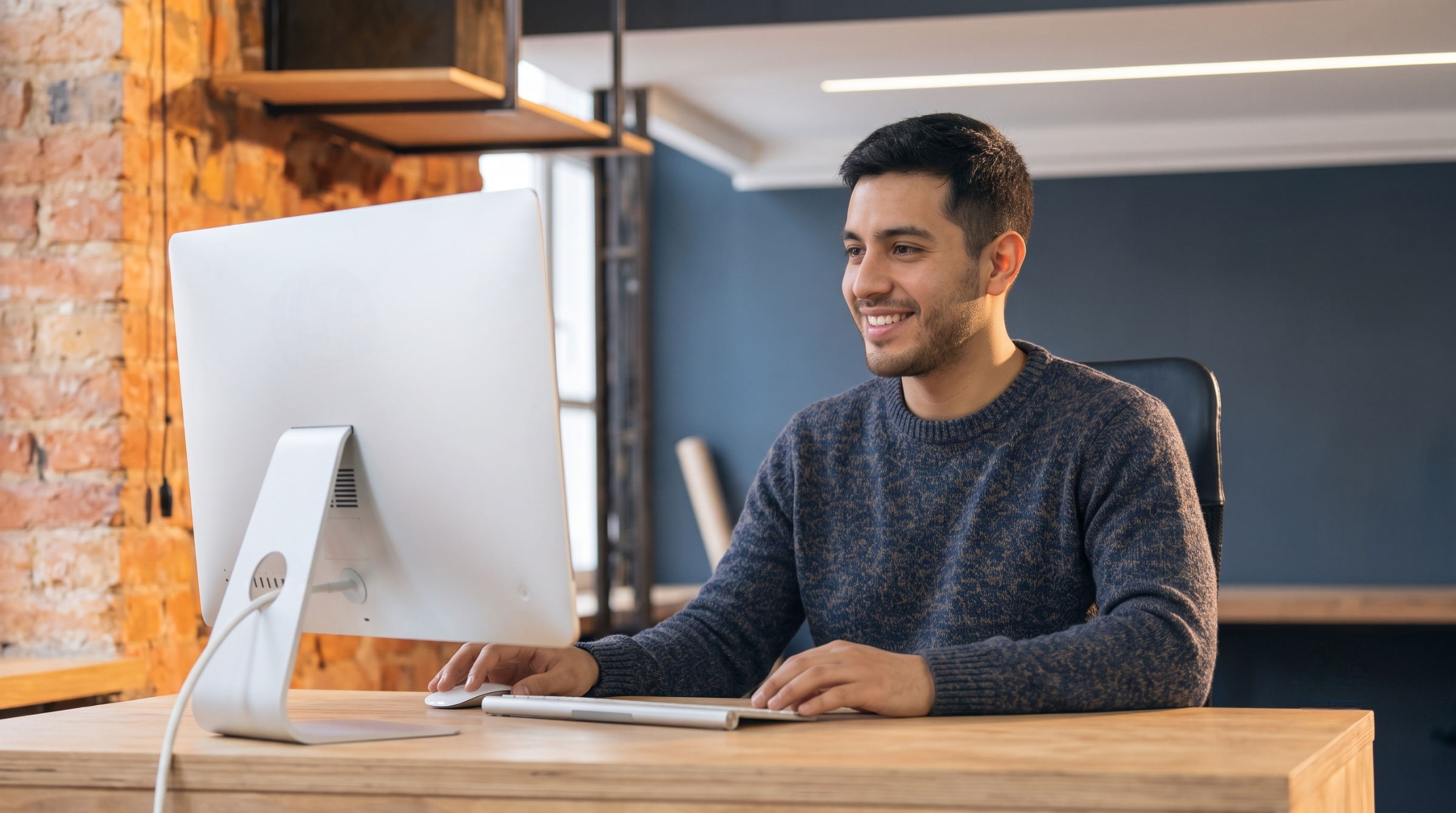 Male virtual lifestyle assistant working on a desktop computer at an office desk