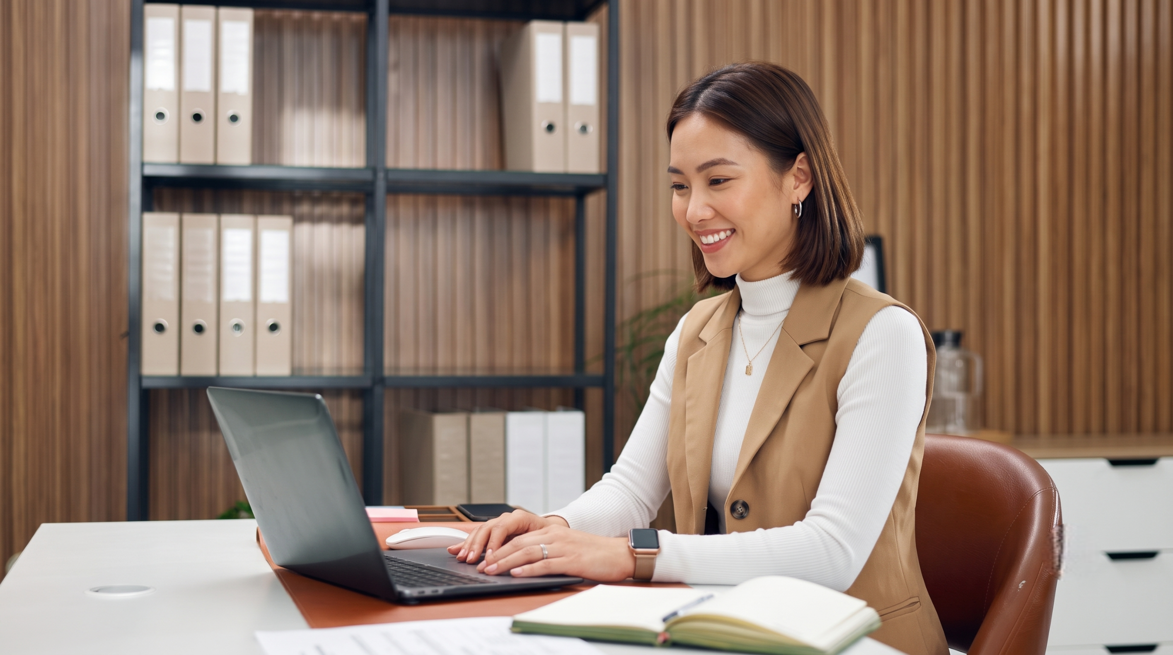 Professional female virtual lifestyle assistant typing on a laptop and organizing files