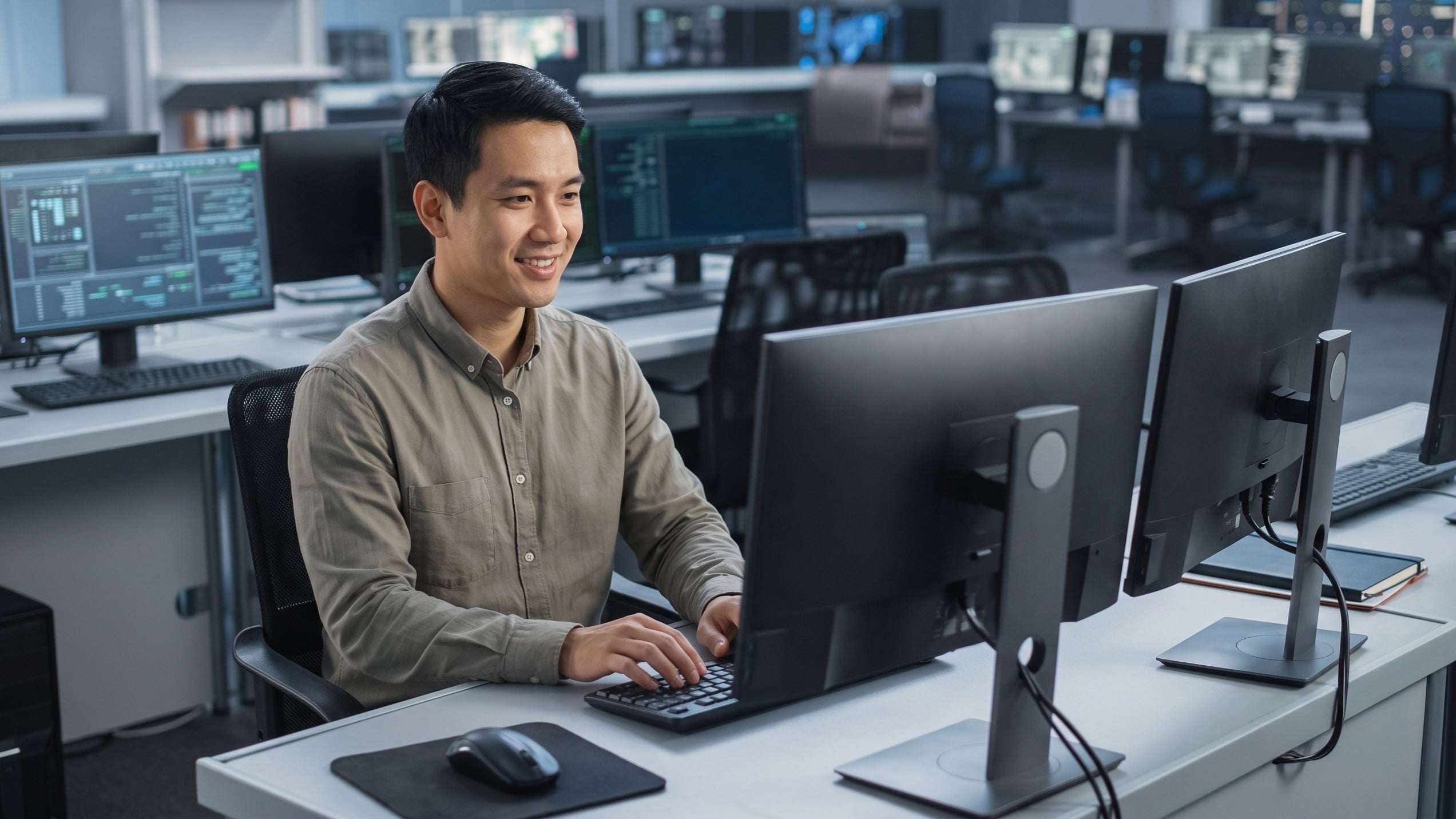 Vietnamese professional in an AI agent manager role at a multi-monitor desk
