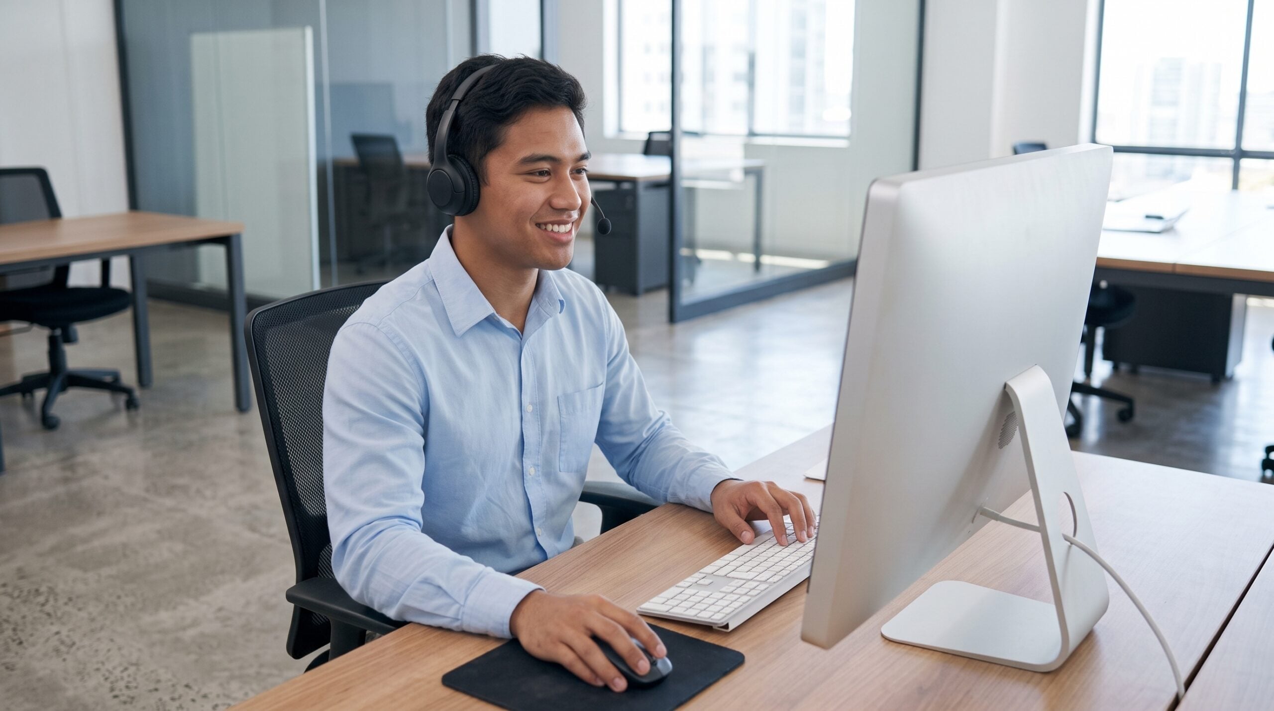 remote order fulfillment specialist with a headset and a large monitor in an open office