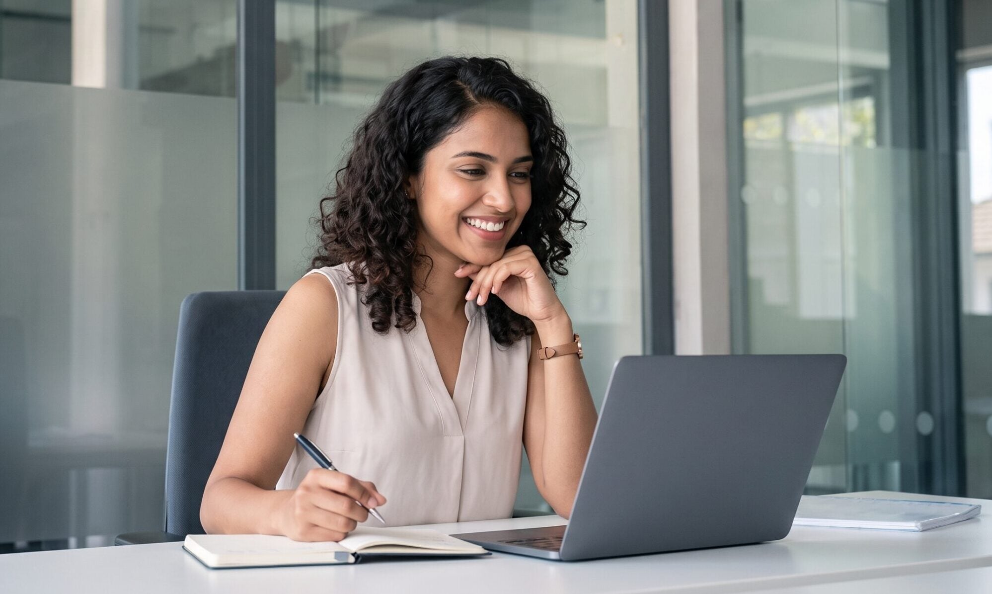 emote investment operations specialist smiling while writing in a notebook