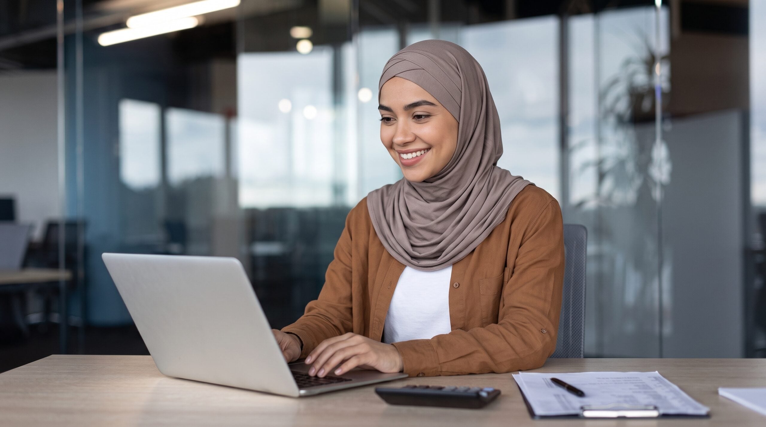 remote investment operations specialist with a hijab typing on a laptop